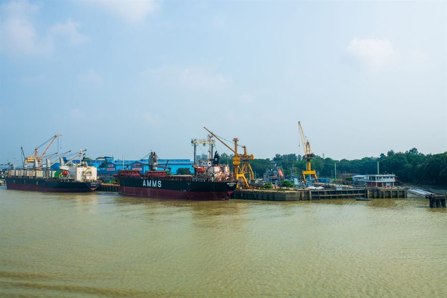Ships moored at a river dry dock with yellow cranes